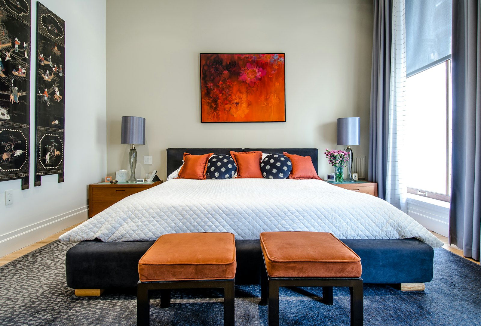 Hotel-style bedroom in deep tones with framed artwork above the bed