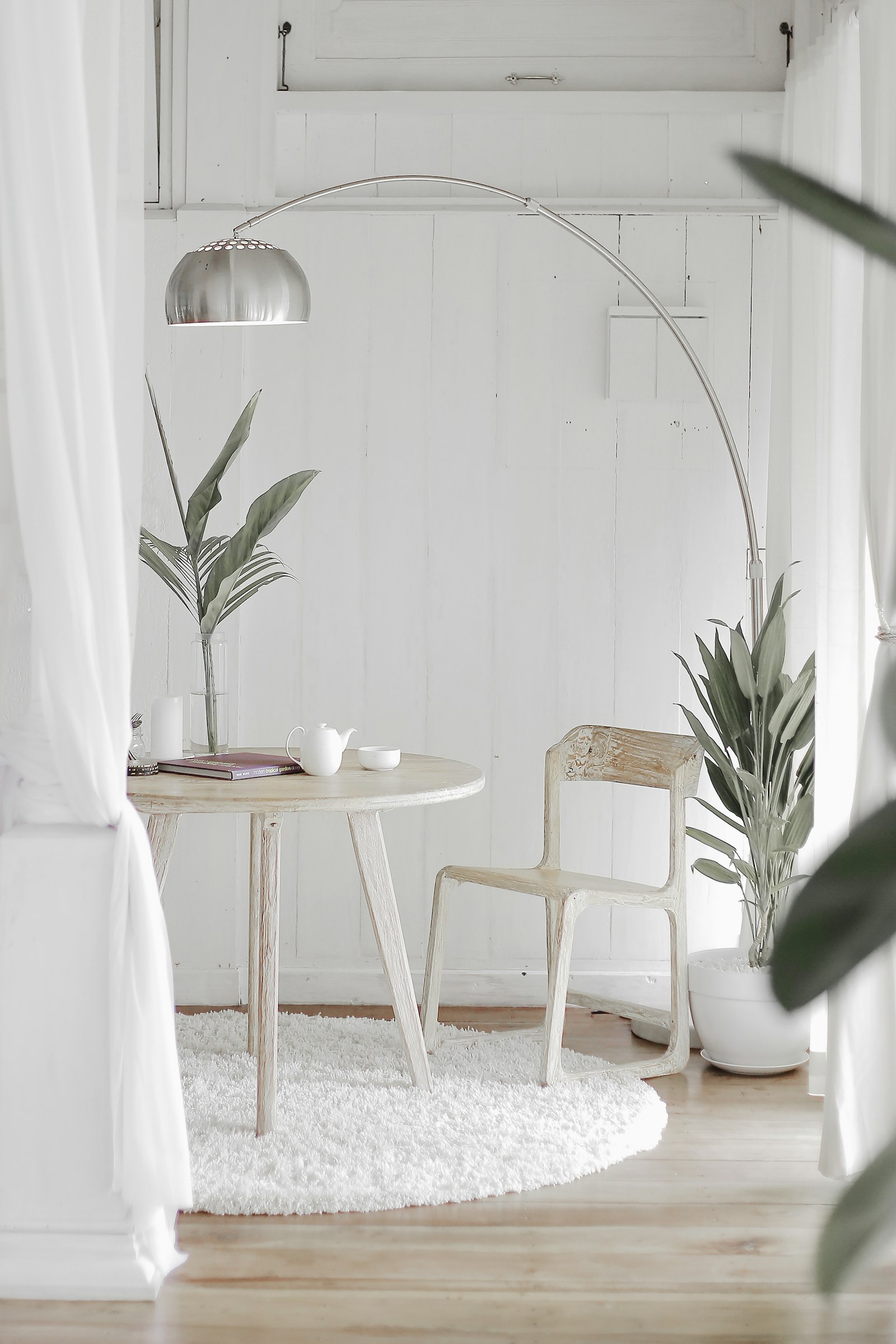 Round white dining table with arched floor lamp and sheer curtains