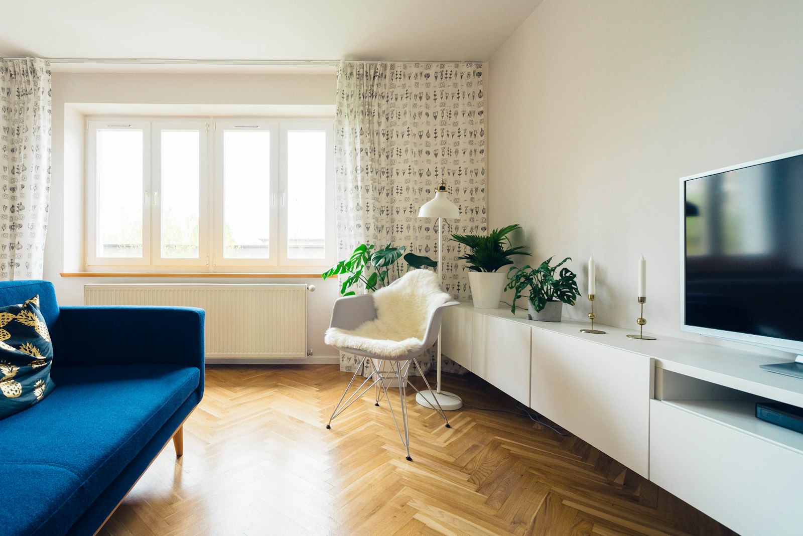 Living room in a five-room BTO flat with a blue sofa and herringbone timber flooring