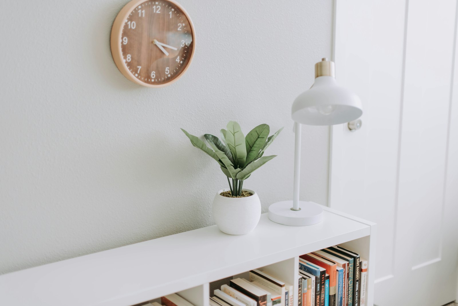Minimal white shelf with wall clock and potted plant