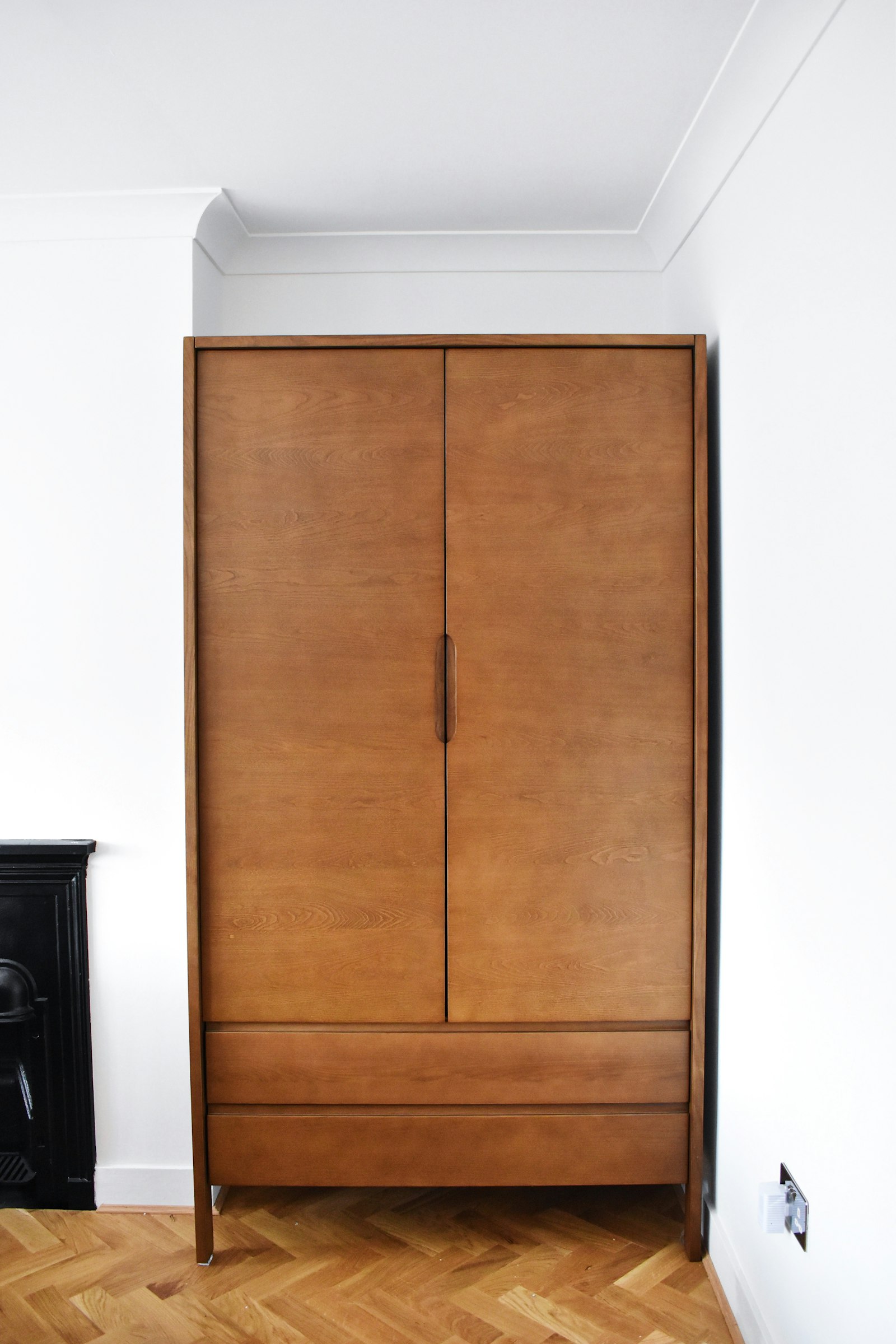 Vertical teak timber grain across full-height wardrobe fronts